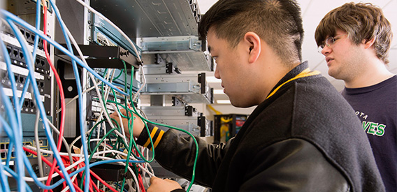 Computer Science student adjusts wires in a server room