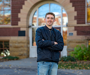 Man in a blue jacket and jeans standing in front of South Hall