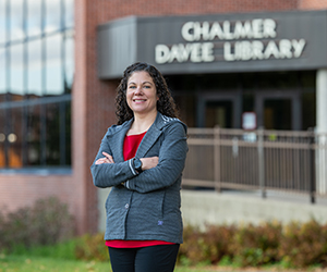 Woman in a red blouse and gray jacket standing in front of the Chalmer Davee Library