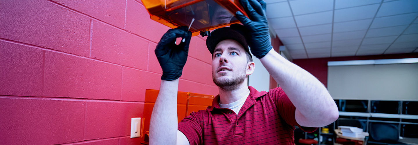 A male student cleans a 3D printing tray with a Q-Tip