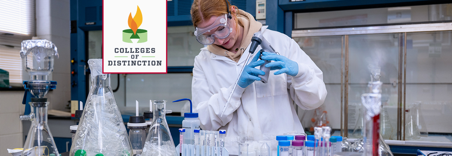 A female student wearing a white lab coat and safety goggles uses a liquid measuring device in a laboratory setting